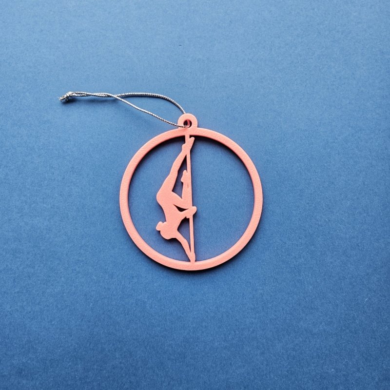 Pink Glow in the Dark Pole Dance Ornament (Pose A) on a blue background. Unique Poledance Christmas Decor