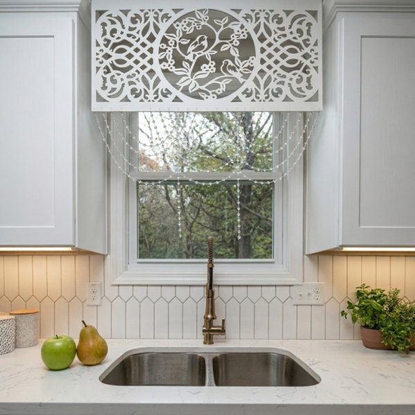 Biały panel ażurowy wycinany laserowo jako nowoczesna dekoracja okna w jasnej kuchni nad zlewem.