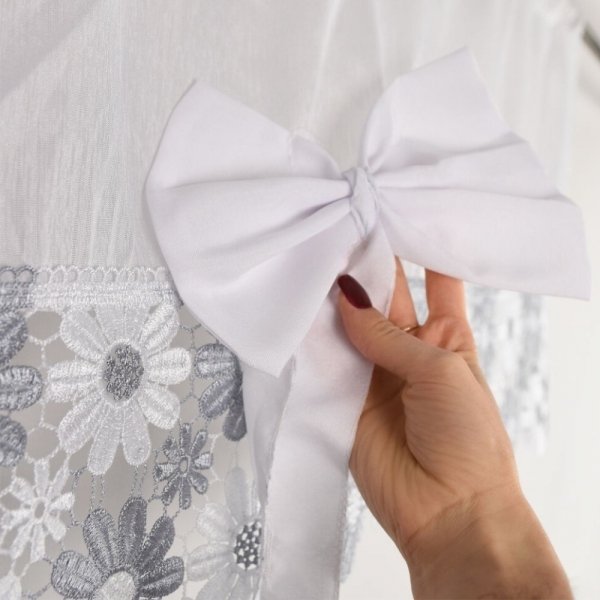 Zbliżenie na dużą, dekoracyjną białą kokardę naszytą na łączeniu materiałów w komplecie Megan.