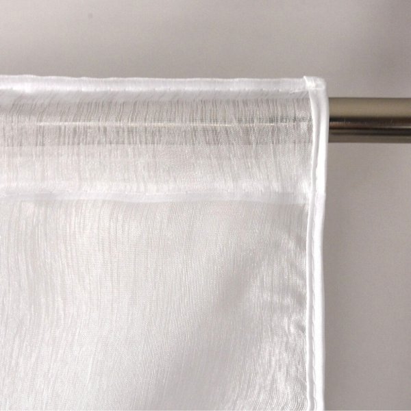 Zbliżenie na strukturę białej tkaniny oraz estetyczne wykończenie tunelu na karnisz rurkowy w firanie Megan.