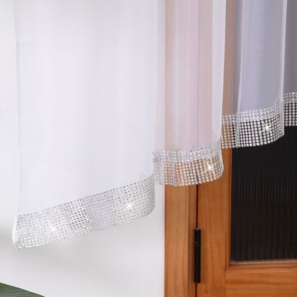 Biała firanka z cyrkoniami zawieszona na oknie – widok na estetyczne ułożenie materiału.