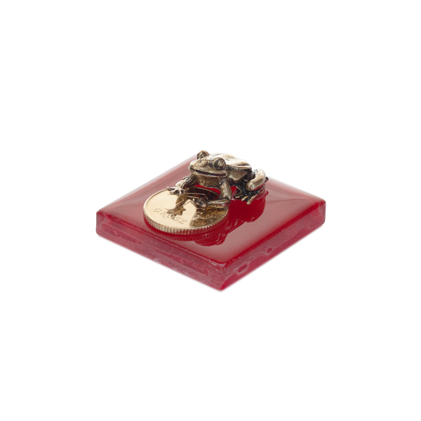 Figurka na szczęście metalowa żaba z grosikiem na szklanym postumencie. Rozmiar 2x4 cm